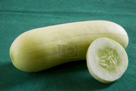 Eine volle mit klein geschnittenen Scheiben grüner Gemüsegurke Kakdi auf grünem Hintergrund