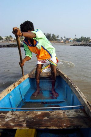Téléchargez les photos : Un pêcheur indien part à la pêche ramant un bateau à Uttan Beach ; Bombay maintenant Mumbai ; Maharashtra ; Inde - en image libre de droit
