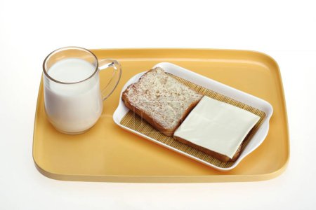 Foto de Taza de leche con pan tostado con mantequilla y rebanada de queso - Imagen libre de derechos