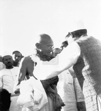 Téléchargez les photos : Mahatma Gandhi accueilli par quelqu'un avec une guirlande de coton khadi mala à l'ashram de Sevagram, vers 1942 - en image libre de droit