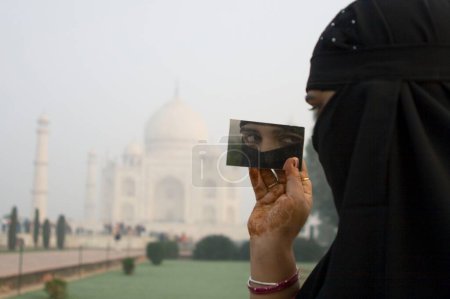 A Muslim woman in front of mogul monument Taj Mahal seven wonder of the world constructed by emperor Shah Jahan ; Agra ; Uttar Pradesh ; India MR707