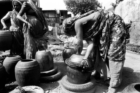 Foto de Las mujeres dan toques finales a las vasijas de barro al horno _ arcilla en Kumbhaewada, Dharavi, Bombay ahora Mumbai, Maharashtra, India. - Imagen libre de derechos