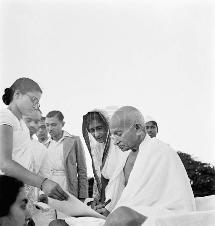 Photo for After prayer Mahatma Gandhi gives an autograph in Pune, 2nd Oct 1944, Abha Gandhi, Rajkumari Amrit Kaur - Royalty Free Image
