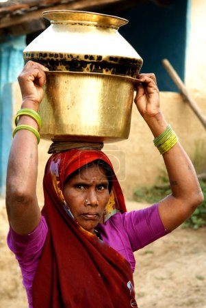 Foto de Mujer llevando agua en macetas de metal; Carm Daksh; Bilaspur; Chhattisgarh; India - Imagen libre de derechos