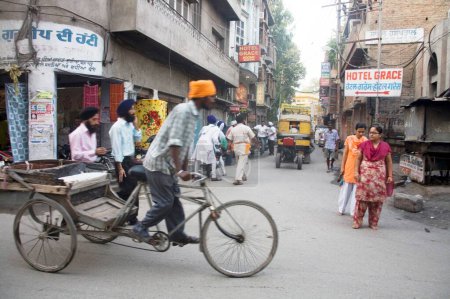 Photo for Street scene cycle rickshaw carrying Sikh man in a lane near Swarn Mandir Golden temple, Amritsar, Punjab, India - Royalty Free Image