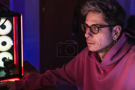 Photo for Young gamer with glasses and pink sweater playing video games all night. - Royalty Free Image
