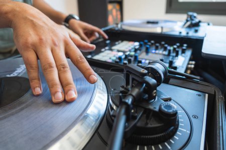 Hands of a DJ playing the turntable in his home studio.