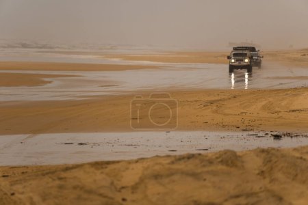 Strand an einem Schlechtwettertag mit zwei Geländewagen im Hintergrund. Fraser Island, Queensland, Australien.