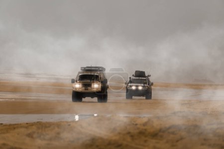 Two 4x4 cars driving along the foggy beach in search of adventure. Fraser Island, Queensland, Australia.