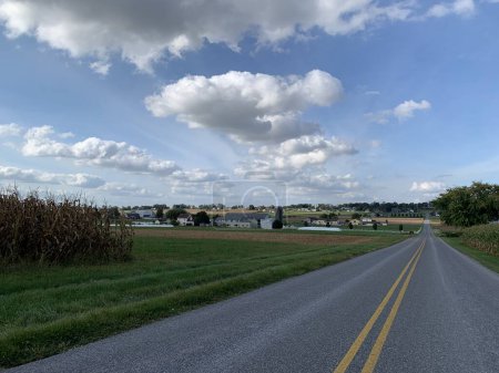 Landstraße im Lancaster County, dem Land der Amischen, mit landwirtschaftlichen Gebäuden und Ackerland an einem bewölkten Nachmittag Anfang Oktober im östlichen Pennsylvania, USA. Für ländliche, landwirtschaftliche und Reisethemen.