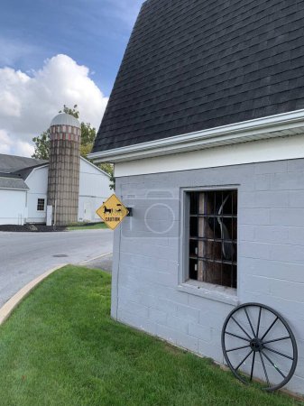 Photo for Lancaster County, Pennsylvania, USA - October 5, 2023:Barn of an Amish farm in Lancaster County which offers buggy rides. A yellow warning sign at the corner rises awarness of possible buggies. - Royalty Free Image
