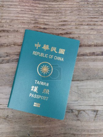 Republic of China (Taiwan) Passport laying on wooden bench with fine grain. Green Taiwanese Passport with Chinese charakters, wooden background.