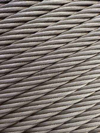 Graues Stahlkabel, Makroaufnahme, vertikal, für Hintergrund und Industrie. Drahtseil besteht aus zwei massiven Metalldrähten, die zu einer Spirale verdreht werden, die ein Verbundseil bildet, in einem Muster, das als aufgelegtes Seil bekannt ist.