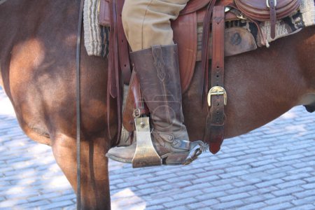 Detalle de cerca de la bota de un vaquero en un estribo de silla de montar, con espuelas, sentado a caballo. Estilo de vida en Fort Worth, Texas