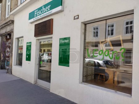 Photo for Vienna, Austria, May 6, 2024: Slogan Vegan? in big green letters is lubrified at display of butcher shop in citycenter of Vienna. Raising attention for the philosphy of abstaining from the use of animal products by provocation and disturbance - Royalty Free Image