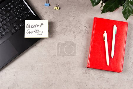 Photo for Quiet Quitting. Workplace desk with office supplies, potted plant, laptop computer with sticker and handwritten text Quiet Quitting. Top view. - Royalty Free Image