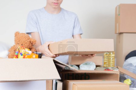 Photo for Teenage boy hands holding blank cardboard box. Volunteer collecting food into donation box. Donation, charity, food bank, help for low income, poor families, migrants, refugee, homeless people. - Royalty Free Image