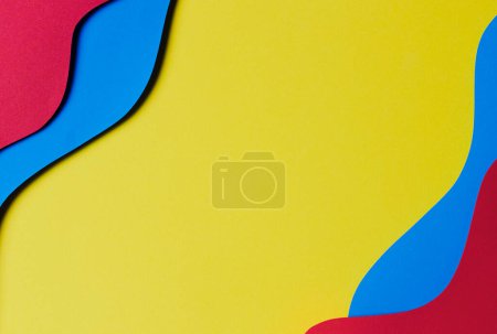 Téléchargez les photos : Résumé fond de texture de papier de couleur. Composition minimale de style de coupe de papier avec des couches de formes géométriques et des lignes en rouge magenta et bleu clair sur fond jaune. Vue du dessus. - en image libre de droit