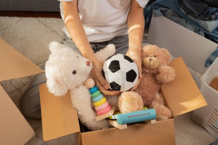 Teenager sortieren und sammeln Kinderspielzeug, Kleidung zu Hause in Kisten. Spenden für wohltätige Zwecke, helfen Familien mit geringem Einkommen, verkaufen online, beziehen ein neues Zuhause, Recycling, nachhaltiges Leben.