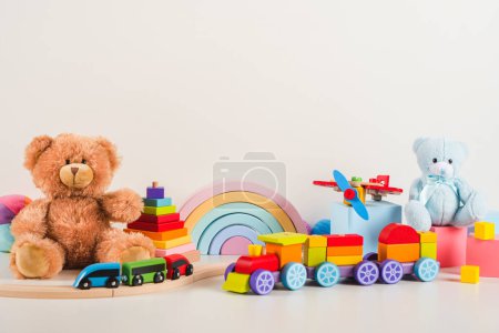 Pädagogische Sammlung von Kinderspielzeug. Teddybär, Eisenbahn, Flugzeug, Regenbogen, hölzerne Musical-, Sinnes-, Sortier- und Stapelspielzeuge auf weißem Hintergrund. Nachhaltiges, umweltfreundliches Spielzeug. Frontansicht.
