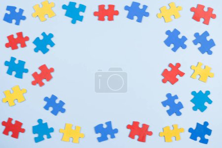 Foto de Blue, yellow, red pieces of puzzle on light blue frame background. World autism awareness day concept. Top view, copy space. - Imagen libre de derechos