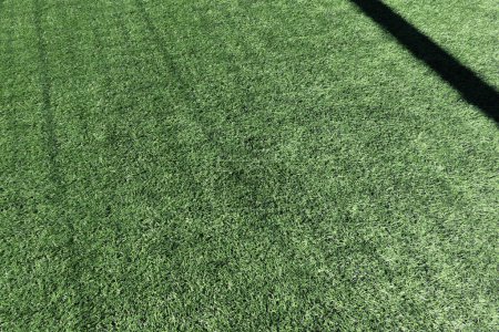 Photo for Artificial turf on football soccer field. Green synthetic grass on sport ground with shadow from soccer goal net. Top view. - Royalty Free Image