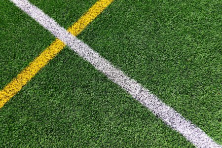 Photo for Green artificial grass turf soccer football field background with white and yellow line boundary. Top view - Royalty Free Image