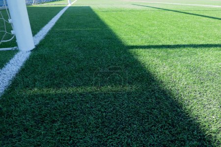 Photo for Artificial turf on football soccer field. Part of soccer goal and green synthetic grass on sport ground with shadow from goal net. - Royalty Free Image