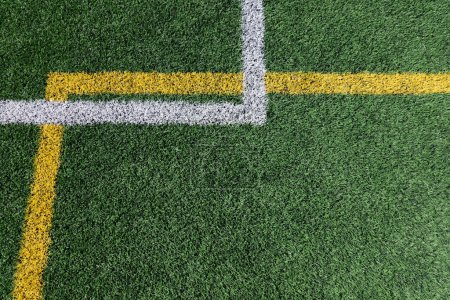 Photo for Green artificial grass turf soccer football field background with white and yellow line boundary. Top view. - Royalty Free Image