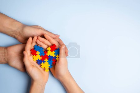 Photo for Woman and child hands holding together colorful puzzle heart on light blue background. World autism awareness day, Autism spectrum disorder concept. - Royalty Free Image