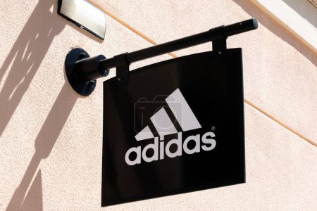 Téléchargez les photos : Orihuela Costa, Alicante, Espagne - 12 avril 2023 : Panneau logo Adidas sur le mur du magasin Adidas. Adidas est une marque multinationale de vêtements de sport qui conçoit et produit des chaussures, vêtements et accessoires. - en image libre de droit