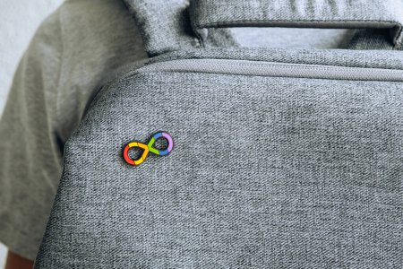 Photo for Teenage boy with autism infinity rainbow symbol sign metallic pin brooch on gray backpack. World autism awareness day, autism rights movement, neurodiversity, autistic acceptance movement. - Royalty Free Image