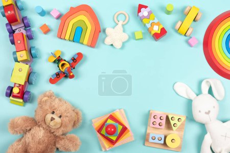 Téléchargez les photos : Bébé enfants cadre de jouet fond. Ours en peluche, jouets éducatifs, sensoriels, de tri et d'empilage en bois coloré pour enfants sur fond bleu clair. Vue de dessus, plan plat. - en image libre de droit