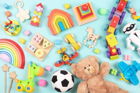 Patrón de juguetes para niños bebé. Conjunto de coloridos juguetes educativos de madera y esponjosos para niños sobre fondo azul claro. Vista superior, plano.
