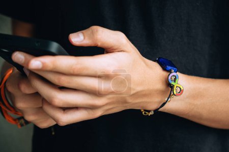 Teenage boy with wristlet with autism infinity rainbow symbol sign on his hand. World autism awareness day, autism rights movement, neurodiversity, autistic acceptance movement.