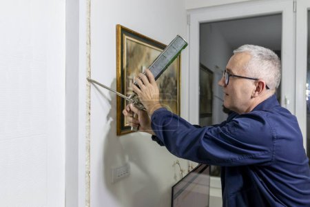 A mature man installing a door frame of an interior door with a polyurethane foam gun. The use of mounting foam with a spray gun in construction works. Apartment renovation
