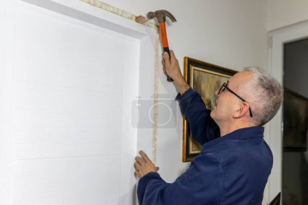 An experienced mature carpenter  installing interior door with a wooden frame at new  apartment. 