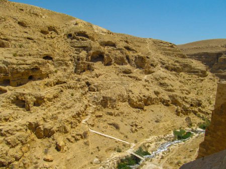 Photo for Kidron river  canyon panorama with monastic cave-cells in the mountain wall viewed from terrace of The Great Lavra of St. Sabbas the Sanctified (Mar Saba) in Judean desert. Palestine, Israel. - Royalty Free Image
