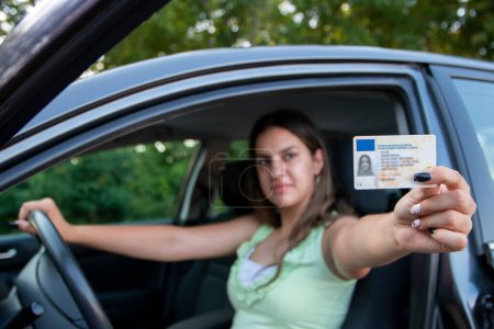 Adolescente montrant son permis de conduire dans la fenêtre de la voiture après avoir passé l'examen ou à la demande de la police de la circulation