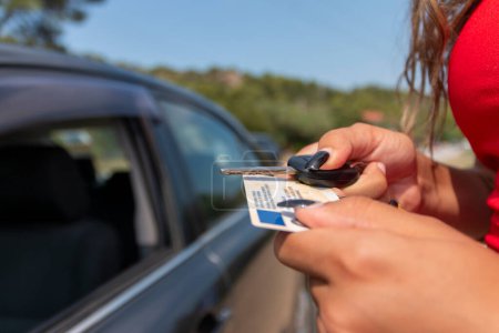 Teenager zeigt nach bestandener Prüfung seinen Führerschein im Autofenster 