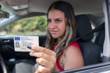 Teenager zeigt nach bestandener Prüfung oder auf Wunsch der Verkehrspolizei seinen Führerschein im Autofenster