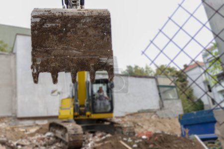 Gran excavadora está llenando un camión volquete con tierra en el sitio de construcción, proyecto en curso.