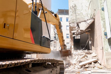 Prozess des Abrisses von Altbauten. Bagger brechen Haus. Zerstörung baufälliger Wohnungen für Neubaugebiete