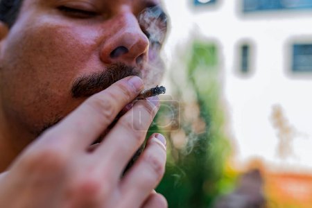 Foto de Un porro en la mano Un hombre fuma marihuana. Conceptos de uso médico de la marihuana y legalización del cannabis
. - Imagen libre de derechos