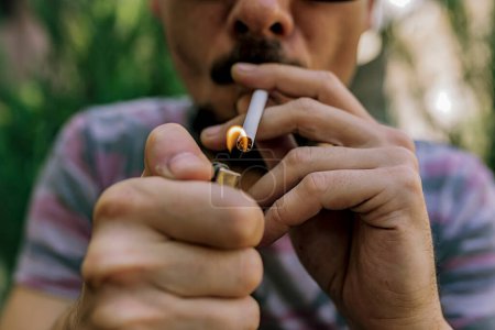 Drogenkonsum, Drogenmissbrauch, Sucht, Menschen und Raucherkonzept. Süchtiger zündet Marihuana-Joint mit Feuerzeug an