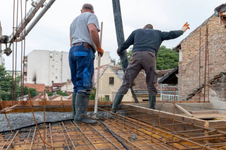 Construction workers pour concrete on rebar using concrete pump. Concreting a building plate with ready-mixed concrete on the construction site of a residential building