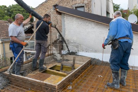 Bauarbeiter gießen mit einer Betonpumpe Beton auf Betonstahl. Betonierung einer Bauplatte mit Transportbeton auf der Baustelle eines Wohnhauses