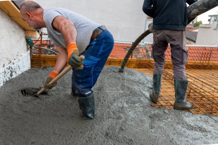 Bauarbeiter gießen mit einer Betonpumpe Beton auf Betonstahl. Betonierung einer Bauplatte mit Transportbeton auf der Baustelle eines Wohnhauses