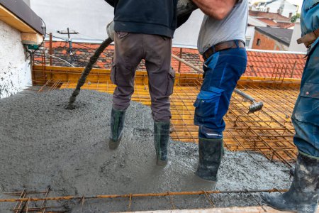 Construction workers pour concrete on rebar using concrete pump. Concreting a building plate with ready-mixed concrete on the construction site of a residential building