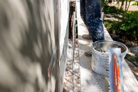 Montage von Bewehrungsnetzen an einer Fassade. Reparatur der Hausfassade, Verputzen der Wände aus expandiertem Polystyrol mit Spezialkleber und Fiberglas